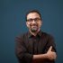 Portrait of a smiling man of Indian ethnicity against a blue wall background. Portrait of a smiling man of Indian ethnicity against a blue wall background.